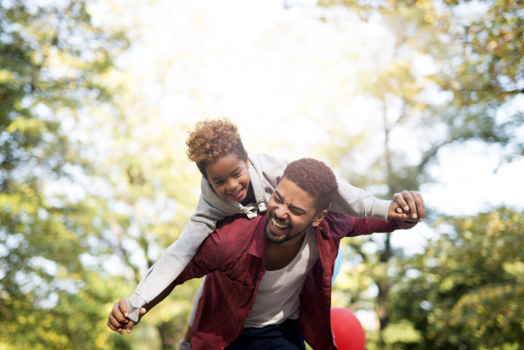 Father holding his daughter on shoulders and laughing.