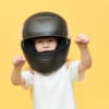 Skillful experienced little girl in safety motorcycle helmet driving motor vehicle very fast, holding hands on steering wheel on handlebar, enjoying high speed. Extreme sports and active lifestyle