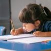 Focused black haired Latin girl sitting at school desk