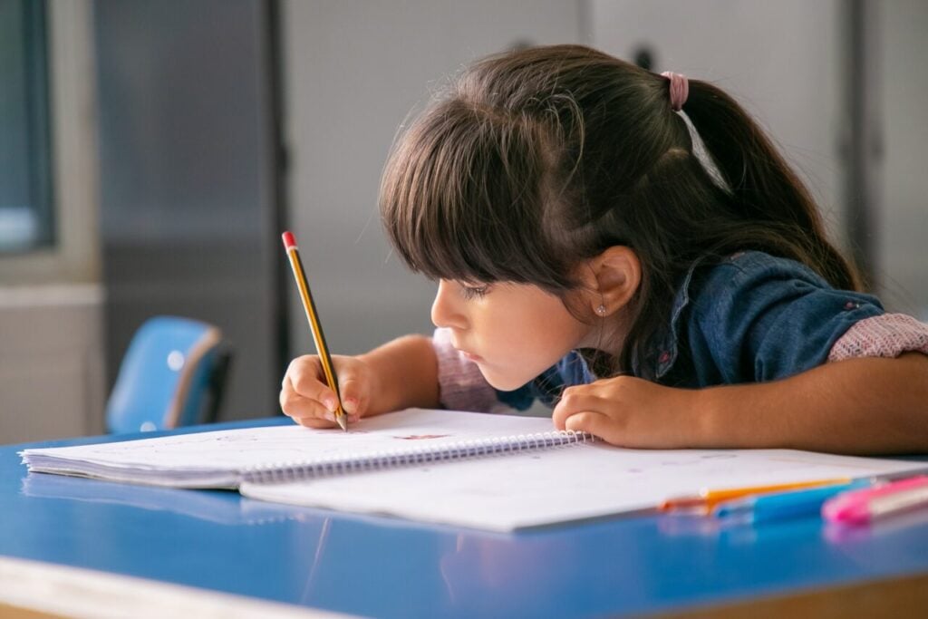 Focused black haired Latin girl sitting at school desk