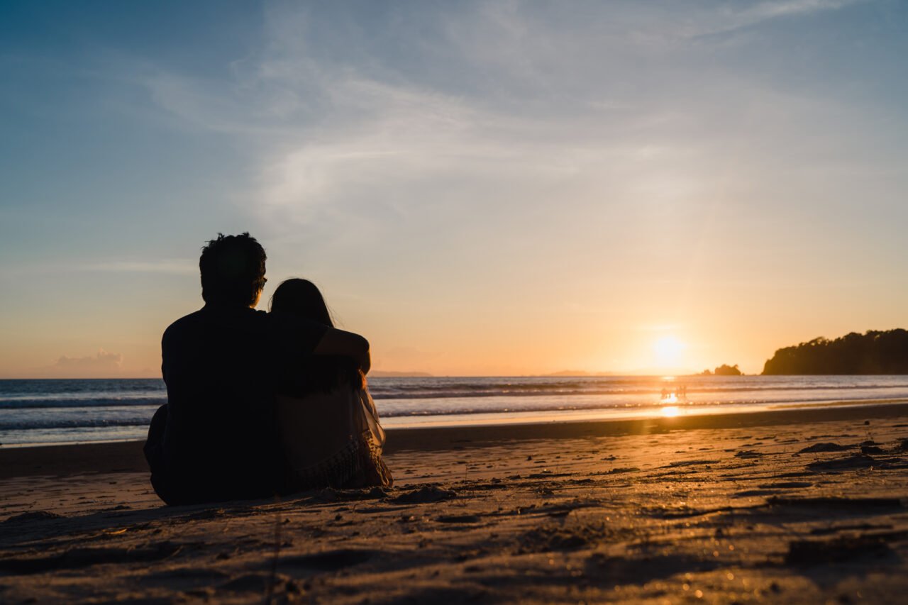 Young Asian couple watching sunset near beach, sweet couple happ